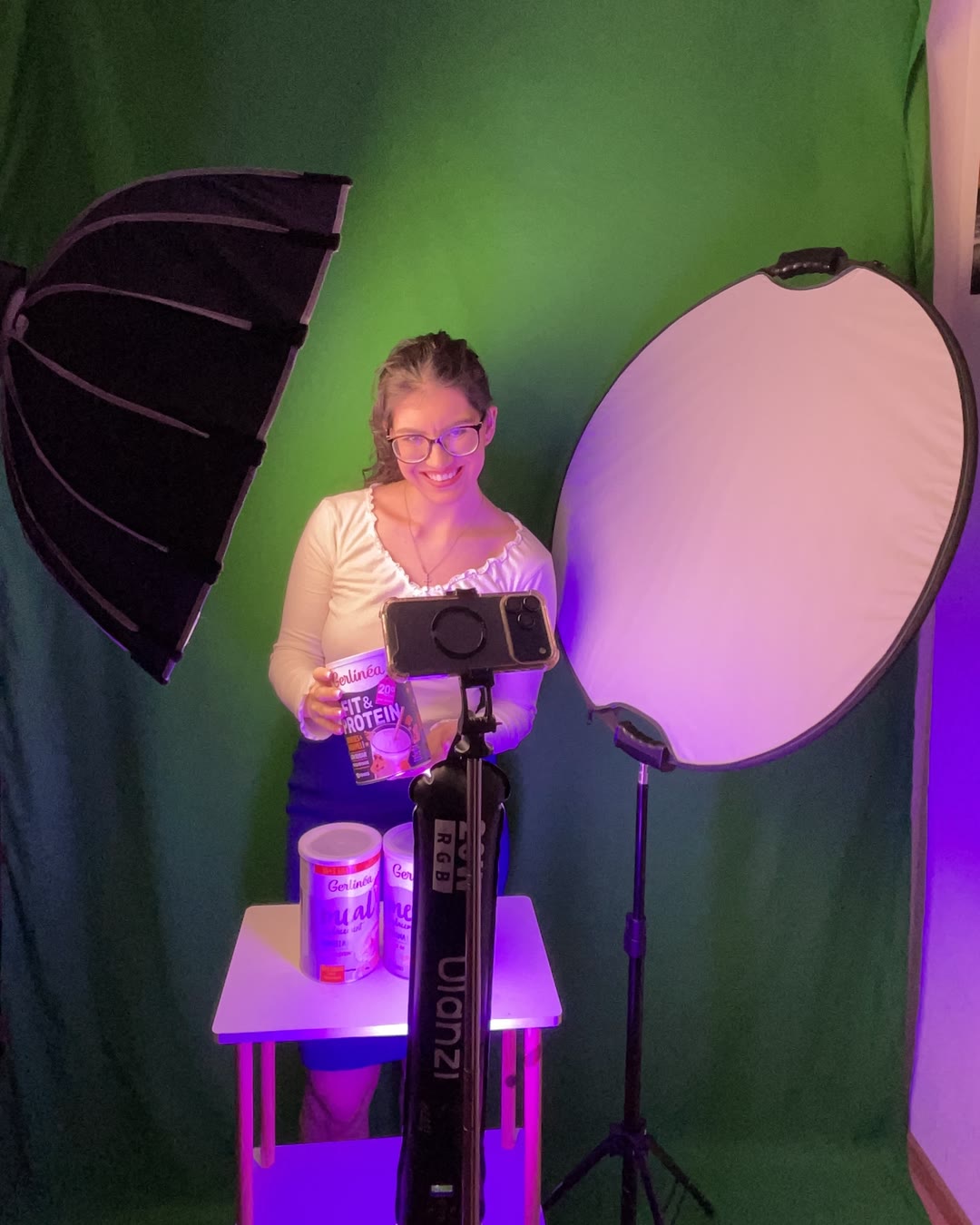 Sophie en plein tournage devant son fond vert, avec softbox, réflecteur et iPhone sur trépied